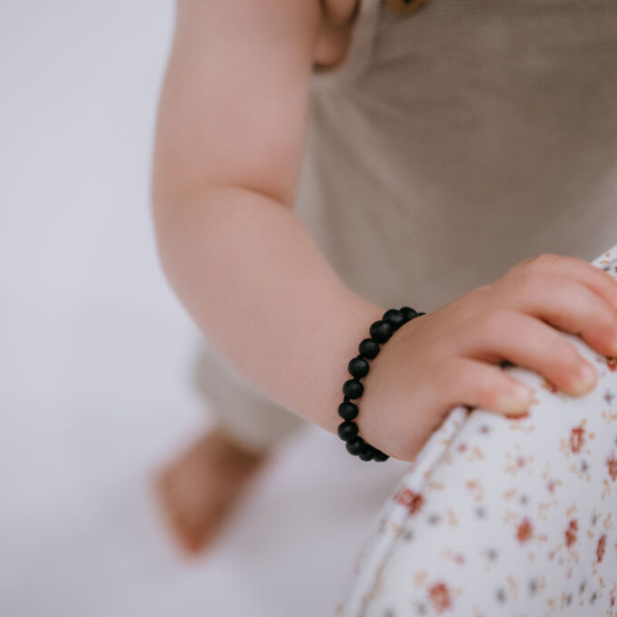 raw black amber teething bracelet on baby arm